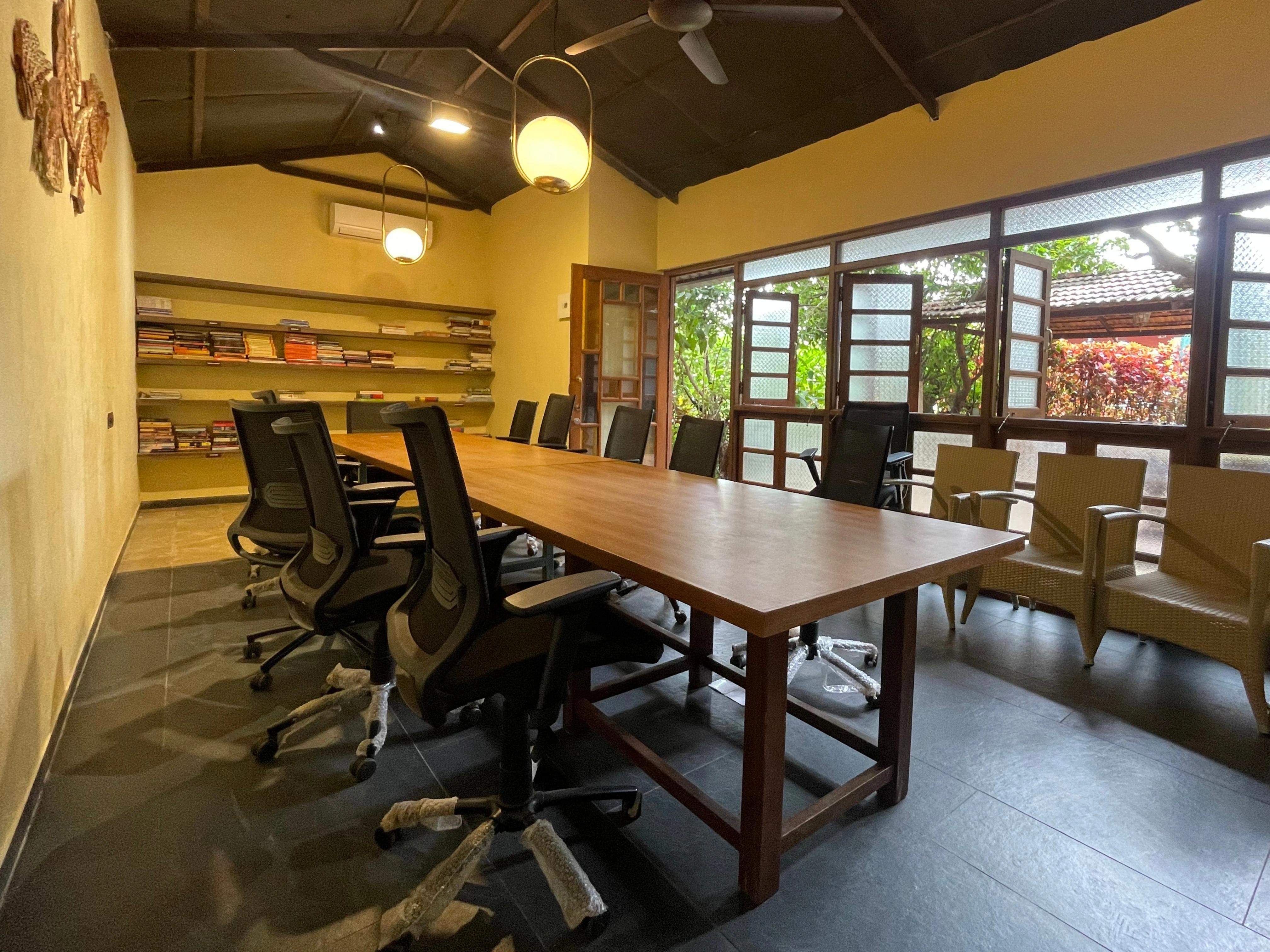 Cozy library space with a large wooden table and shelves filled with books at Ramsukh Resort.